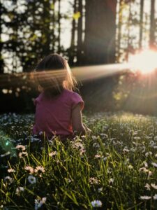 Child sitting in a flower field, a beautiful picture of how to calm mind from all distractions.