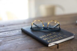 Notebook and glasses on wooden table inspiring you to believe in yourself.