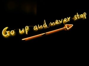 Neon sign with motivational message focusing on consistency and growth.