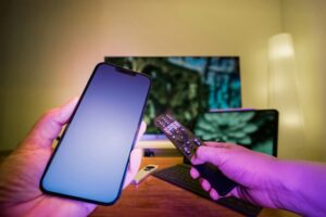 Hand holding phone and remote control , the main reasons for distraction.