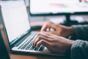 Person typing on a laptop keyboard, depicting best digital skills to learn to make money online.