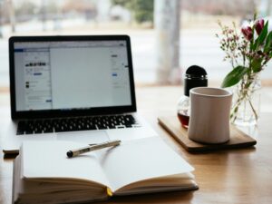 Laptop, notebook, pen, coffee cup, a perfect setup for finding out best free tools for online work beginners.